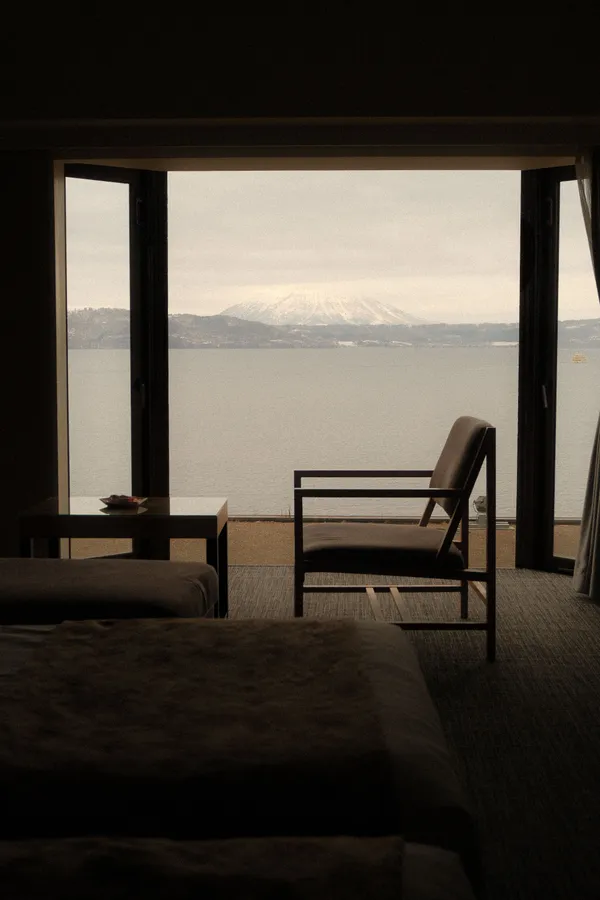 Minimalist luxury hotel suite with floor-to-ceiling windows and soft natural light