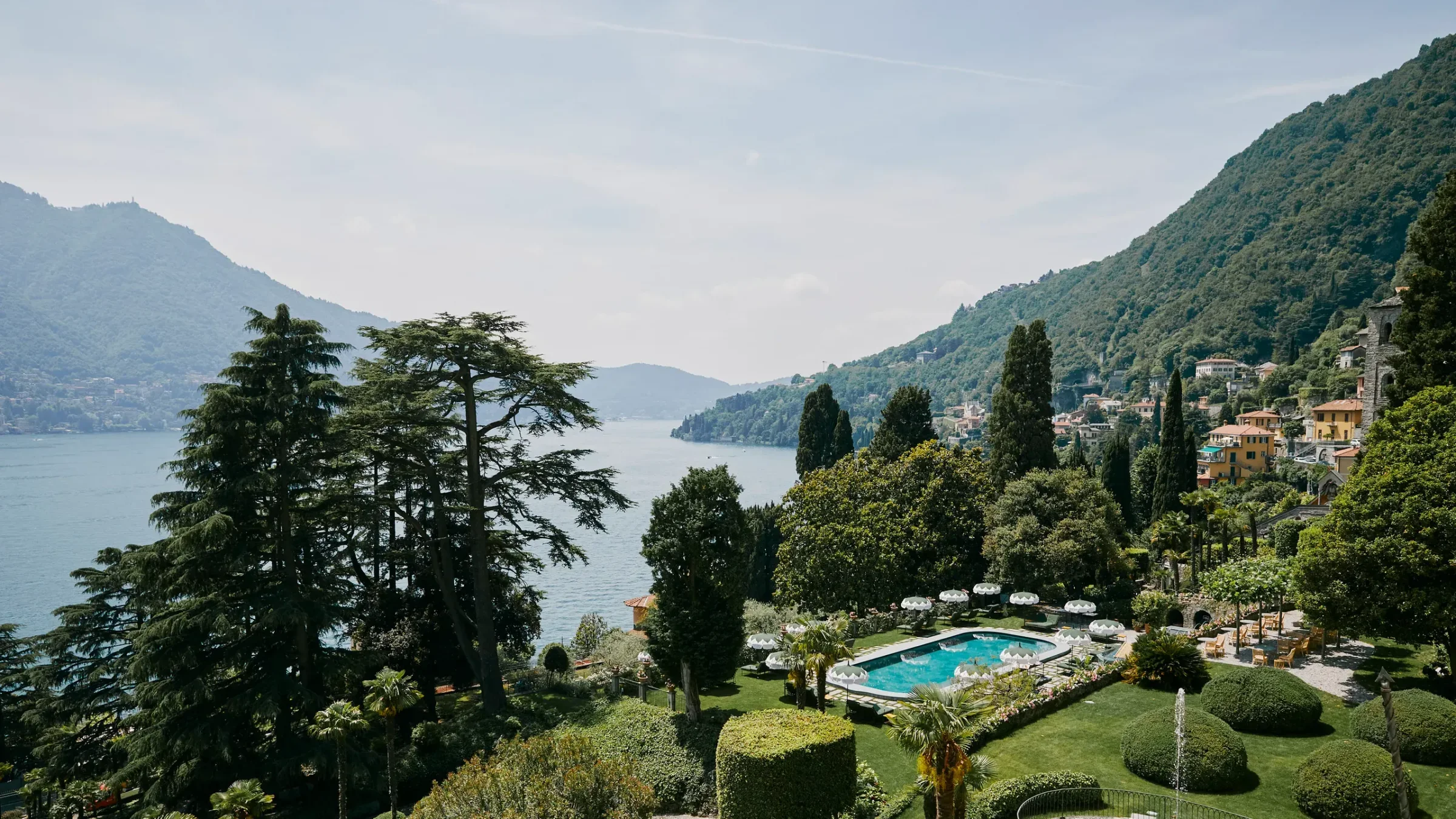 Neoclassical yellow facade of the historic Villa Passalacqua and its manicured Italian gardens overlooking Lake Como in Moltrasio, Italy.